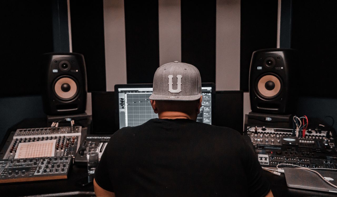 A music producer working in a recording studio surrounded by professional audio equipment.