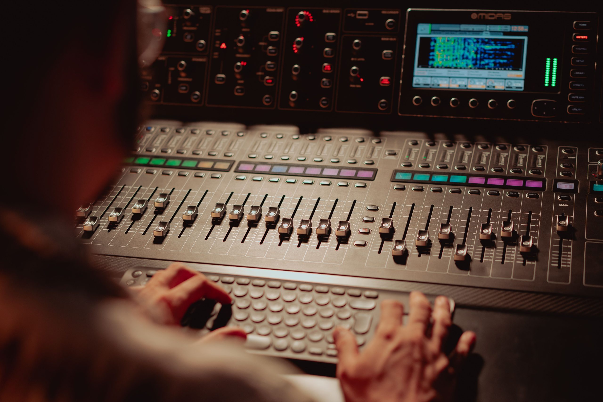 Close-up of an audio engineer working on a professional sound mixing console in a recording studio.