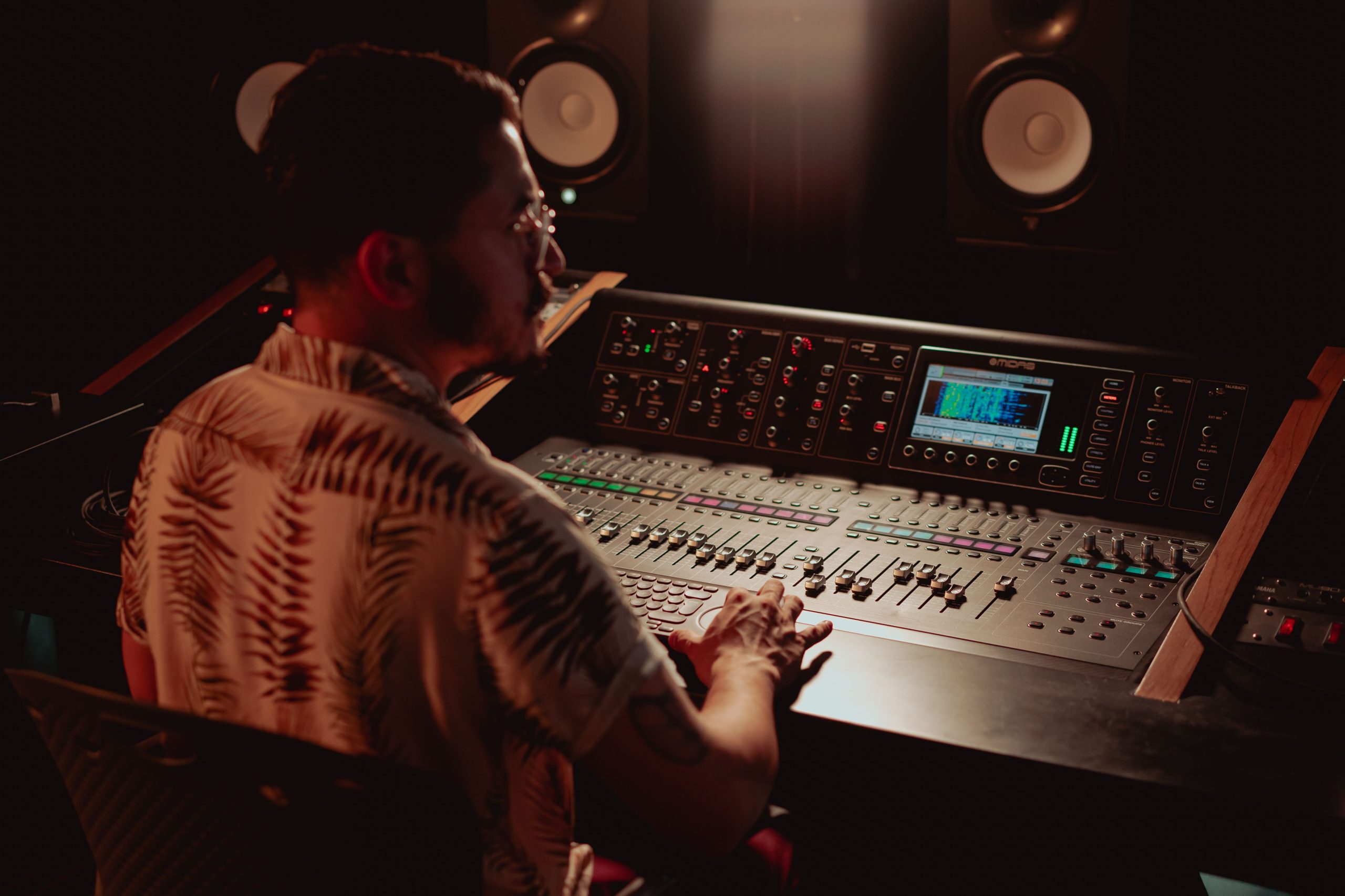 Audio engineer working in a modern recording studio, adjusting an advanced audio mixer with focus and precision.